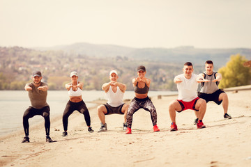 Wall Mural - Group Friends Exercising On The Beach