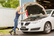 Blonde haired woman in jeans working on a car