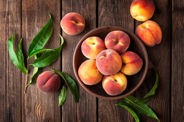 Canvas Print - Fresh juicy peaches with leaves on dark wooden rustic background