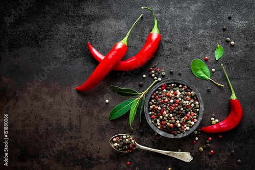 Fotografía Red hot chili pepeprs and peppercorns on black metal background, top view