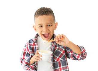 Wall Mural - Cute African American boy eating yogurt on light background