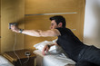 © theartofphoto - Serious Gorgeous Young Man Connect his Mobile Phone to a Charger While Lying on his Side on the Bed.