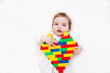 © ulza - baby cute girl  holds heart with lots of colorful plastic blocks constructor.  Love heart for valentine background. .