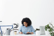 © wayhome.studio  - Attractive young African American female accountant wearing blue shirt and eyeglasses working on financial report at her white office, making calculations and hand writing, looking concentrated