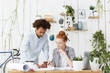 © wayhome.studio  - People, teamwork, creativity, partnership and cooperation concept. Confident experienced dark-skinned chief architect helping beautiful young redhead female trainee to make drawings in white office