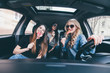 © F8  \ Suport Ukraine - Three beautiful young cheerful women looking at each other with smile and holding lollipops while sitting in car