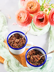 Red quinoa with vegetables in enamel mugs. Vegetarian gluten free lunch