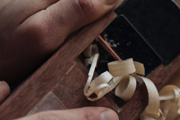 Wood carving, the master's hands work with a wooden surface, a professional does wood crafts