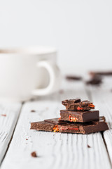 Wall Mural - Raw handmade chocolate with goji, cup of tea or coffee on white wooden background. Healthy morning with sweets