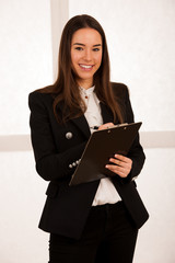 Asian caucasian busines woman writing on a clipboard