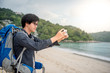 © zephyr_p - Young Asian backpacker man take photos of beach and sea by smartphone, summer holiday vacation and travel tropical island concepts