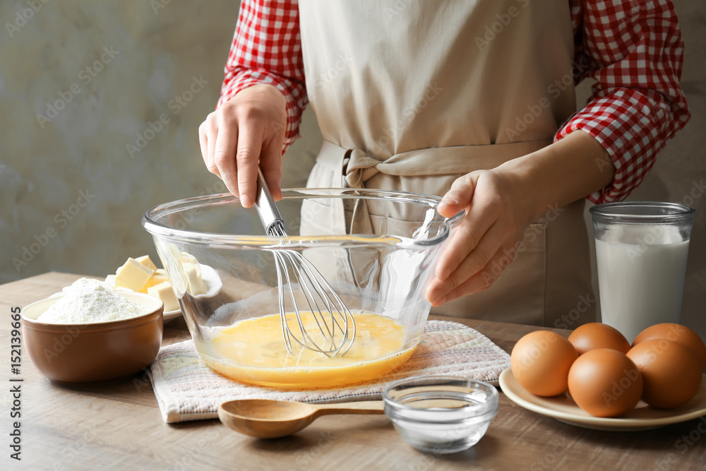 Woman making dough for a pie in bowl on table