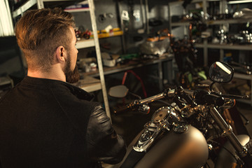 Wall Mural - Handsome bearded man on his motorbike at the workshop