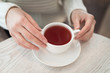© Roman Penderev - Female hands holding a white cup of tea standing on the table top view