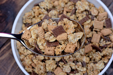 Muesli with chocolate in a spoon and bowl on table