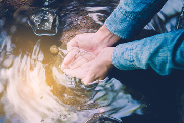 close up Water in the hands of women. Woman taking clear water in the Small stream hands