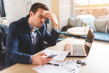 Concerned businessman looking at mobile in office