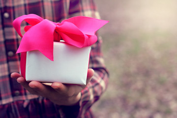 greeting with a surprise/ holiday gift with a red ribbon in the hand