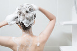 woman in shower washing hair with shampoo