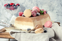Three Layers Vanilla, Coffee And Chocolate Ice Cream Cake, Served With Frozen Berries And Macaroons Biscuits On Rectangular White Plate, Textile Napkin Over Gray Texture Background.