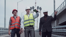 4K Shot Of Diverse Group Of Three Handsome Male Construction Engineers With Serious Expressions Walking On Highway Ramp