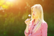 © bluebeat76 - Beautiful young woman blowing seeds from a flower dandelion