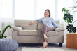 © ArtFamily - Woman in fashionable clothes sitting on sofa in bright living room