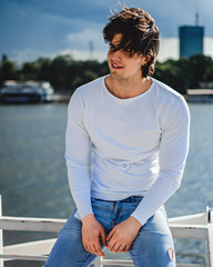 Muscled man sitting on the fence and smiling in the wind