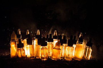 Vape concept. Smoke clouds and vape liquid bottles on dark background. Light effects.