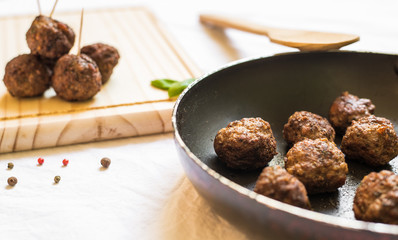 Wall Mural - Cooked meatballs in a frying pan and wooden board