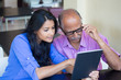 © ashtproductions - Closeup portrait, sitting young woman showing elderly with black glasses to use portable device,scrutinizing data with great concern, isolated indoors background