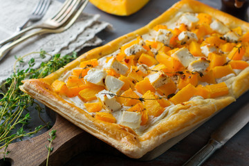 Tart with pumpkin, feta, ricotta cheese and thyme on a dark concrete background. Top view. Selective focus.