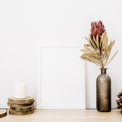 Wall Mural - Front view blank mock up of photo frame with protea flower and trendy stuff at white background. Minimalistic decorated home office concept.