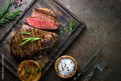Cuadros en Lienzo Grilled beef steak on wooden board. Top view copy space.
