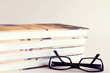 A pile of books with reading glasses
