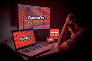 Wall Mural - Young Asian male frustrated, confused and headache by WannaCry ransomware attack on desktop screen, notebook and smartphone, cyber attack internet security concept