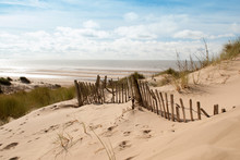 Image Of Sea Viewed From The Top Of A Sand Dune With An Old Broken Fence Running Down It

