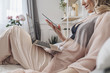 © LUMINA IMAGES - Woman wearing lingerie reclining on bed and using smartphone and laptop