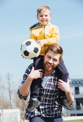 Happy father carrying his little son on shoulders