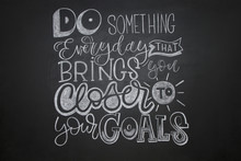Inspirational Quote "Do Something Everyday That Brings You Closer To Your Goals " Written In Lettering Style At Black Chalkboard Background.