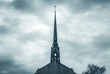 Church steel brass spire. Church building roof with spire and holy cross. Cloudy moody sky background. Minimal architecture design and detail. Exterior design and detail. Abstract architecture. 