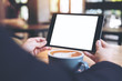 © Farknot Architect - Mock up image of business woman's hands holding black tablet with white blank screen and coffee cup on wooden table in cafe