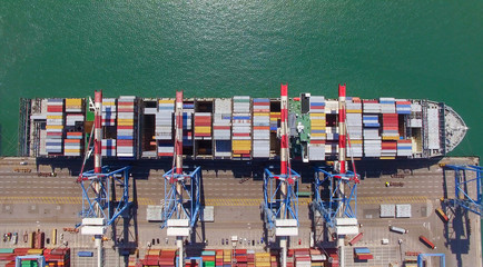 Wall Mural - Commercial port with container ship during loading and unloading - Top down view.