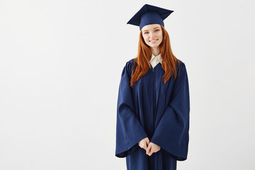 Happy redhead female graduate smiling over white background. Copy space.