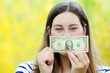 Beautiful young woman with one dollar bill isolated on natural background. Financial reward concept.