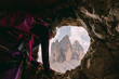 Kletterer schaut aus einer Höhle vom Paternkofel Klettersteig auf die Drei Zinnen, Italien