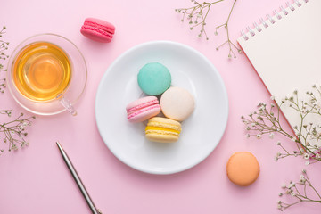 Sticker - Flatlay of notebook, cake macaron, cup of tea and flower on pink table. Beautiful breakfast with macaroon.