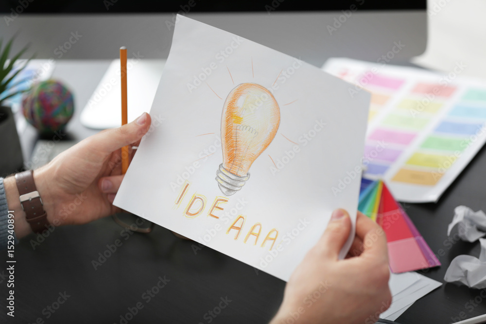 Young male designer holding sketch in office, closeup