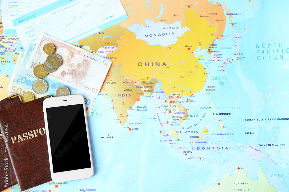 Composition with smartphone, passports, money and arrival cards on world map background
