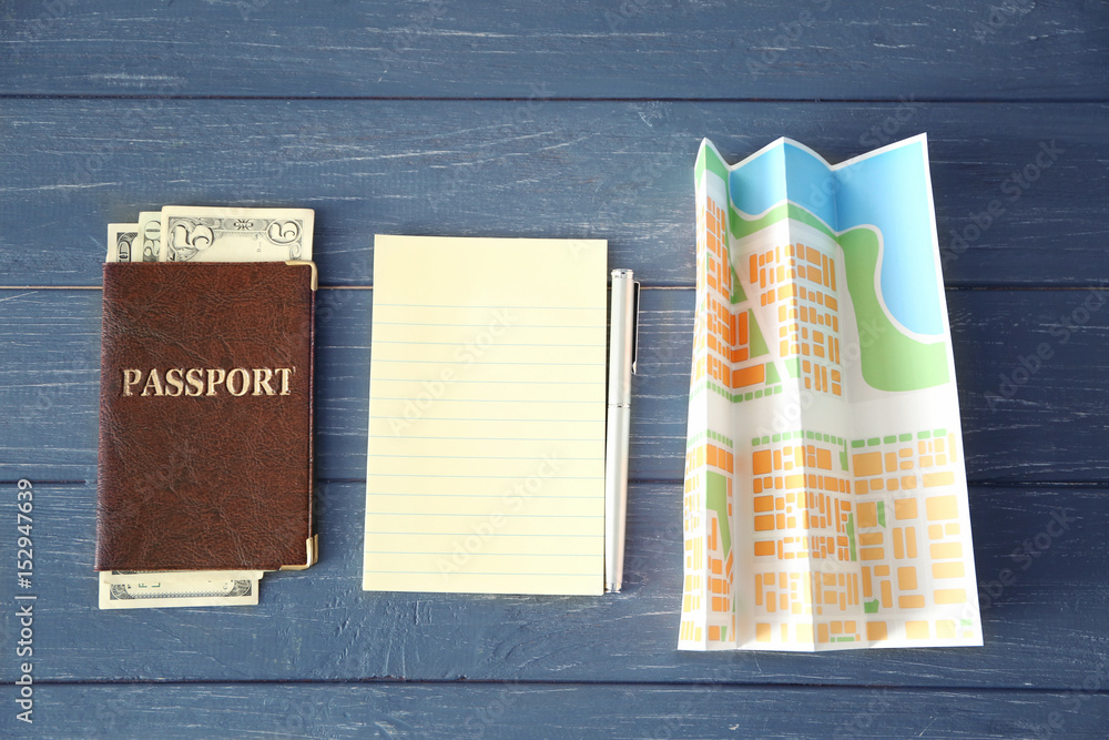 Travel concept. Passport, blank notepad page and map on wooden background